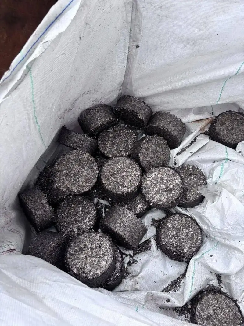 Looking down into an open white FIBC big bag filled with cylindrical metal briquettes.